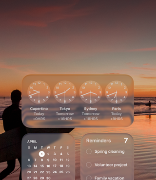 Écran macOS Tahoe affichant les widgets Horloge, Calendrier, Rappels et Météo en Liquid Glass avec en arrière-plan un surfeur marchant sur la plage au coucher du soleil