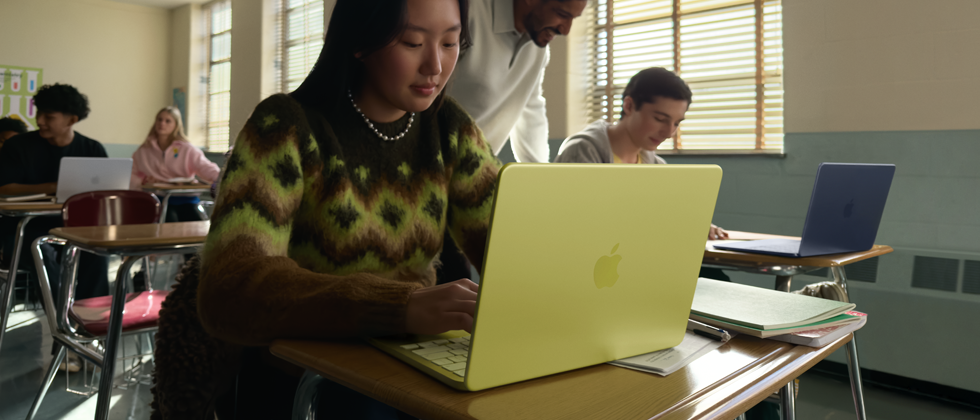 Une étudiante utilise un MacBook Neo, couleur jaune agrume, débranché, dans une salle de classe