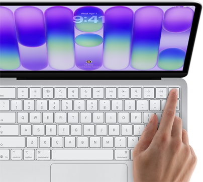 MacBook Neo, couleur argent, affichant l’écran de connexion, doigt d’une personne sur le capteur Touch ID situé dans le coin supérieur droit du clavier